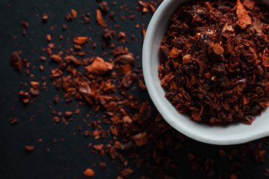 Siyah arka planda izole edilmiş beyaz bir seramik kasede kırmızı biber.