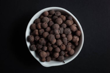 Beyaz seramik kasedeki tüm baharatlar siyah arka planda izole edilmiş.