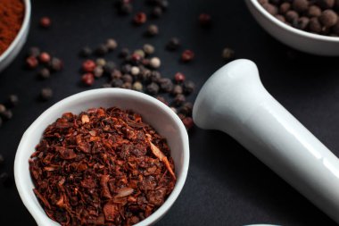 Paprika baharatı seramik bir kasede bezelyelerin yanında seramik bir havan topunda biberli mısır ve karanfil tohumlarıyla saçılmış.