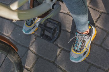 Parlak spor ayakkabılı ayaklar bisiklet pedallarının yanında.
