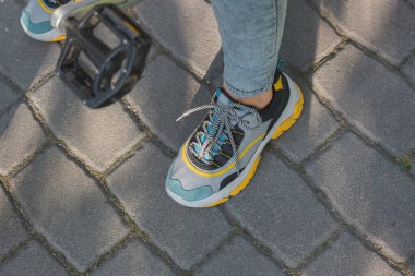 Parlak spor ayakkabılı ayaklar bisiklet pedallarının yanında.