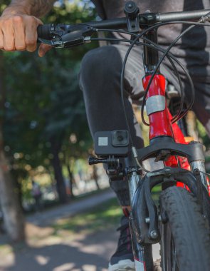 Aksiyon kamerası, adamın bindiği bisikletin tekerleğinin yanında duruyor.