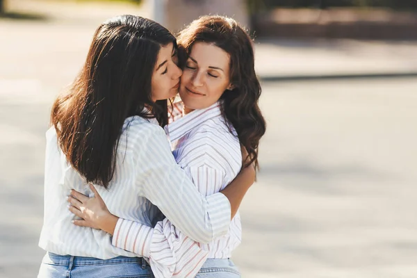 Birbirine aşık mutlu bir çiftin portresi. Sıradan kıyafetler giymiş, kucaklaşan ve öpüşen iki kadın.