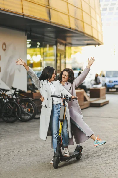 Mutlu yetişkinler eğlenceli arkadaşlar turistler çeşitli kadınlar şehirde scooter 'a biniyor ve günlük kıyafetlerle eğleniyorlar.