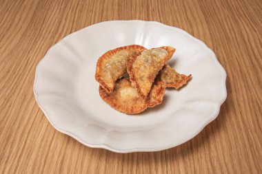 Safran ve bademle tavuklu börek, zeytin yağında kızartılmış ve siyah sarımsak tozu ve maydanozla süslenmiş.