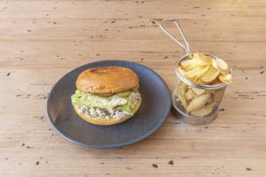 Açık hava pikniğinde esnaf çöreği, sığır eti ve aile yadigarı domatesli bir hamburger fotoğrafı.