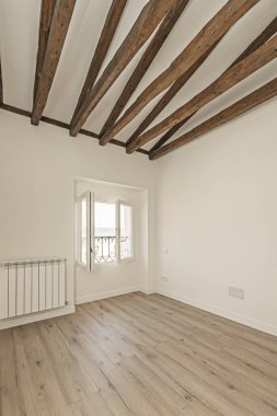 100 yıllık ana kirişleri olan yenilenmiş bir oda. Koyu renk ahşap, modern beyaz boyalı duvarlarla çelişiyor.