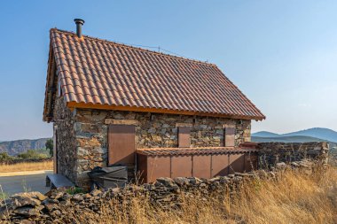 Mountain house with an original stone facade, a plot enclosed by a retaining wall and a traditional orchard with fruit trees