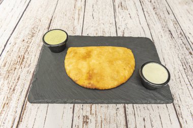Golden and crispy corn flour empanadas filled with shredded chicken, accompanied by whey and creamy guacamole