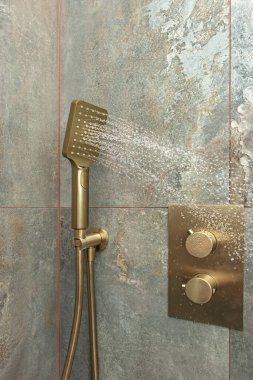 Luxury bathroom with modern brushed brass faucets integrated into a gray-veined Statue marble countertop and a frameless inset mirror