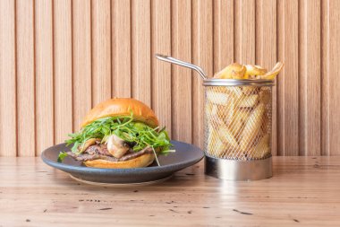 Eski bir inek madalyonlu gurme burger, erimiş Tetilla peyniri, Raff domatesli ve meyveli marullu çörek.