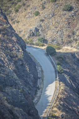 Doğal kıvrımları takip eden, aromatik çalılar ve küçük akarsular arasındaki dağlık araziye adapte olan sıkıştırılmış toprak bir yol.
