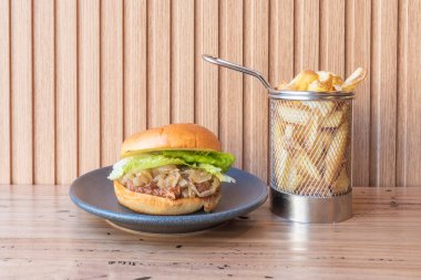 Biftekli el yapımı burger, erimiş peynir, dilimlenmiş domates ve tereyağlı marul. 