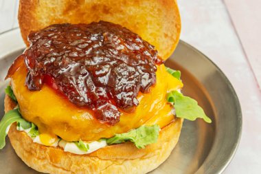 Biftek, erimiş peynir, aile yadigarı domates ve el yapımı brioche ekmeğine bebek marulu hamburger.