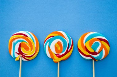 Mavi bir arka plan üzerinde renkli lolipop. Kırmızı, beyaz ve mavi çizgili bir şeker. En az kavramı. Şeker dükkanı serisi.