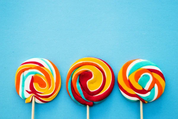 Mavi bir arka plan üzerinde renkli lolipop. Kırmızı, beyaz ve mavi çizgili bir şeker. En az kavramı. Şeker dükkanı serisi.