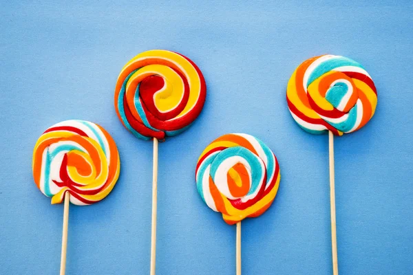 stock image Colorful lollipop on a blue background. Red, white and blue stripes on a candy. Minimal concept. Candy shop series.