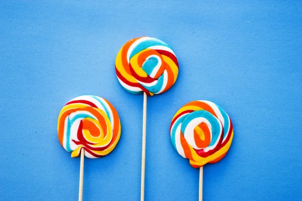 Färgglada lollipop på en blå bakgrund. Röda, vita och blå ränder på en godis. Minimal koncept. Candy shop-serien. — Stockfoto