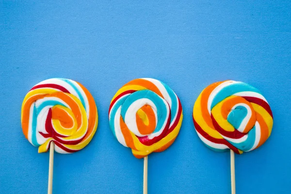 Colorful lollipop on a blue background. Red, white and blue stripes on a candy. Minimal concept. Candy shop series. Stock Image