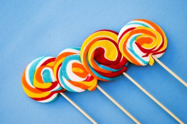 Mavi bir arka plan üzerinde renkli lolipop. Kırmızı, beyaz ve mavi çizgili bir şeker. En az kavramı. Şeker dükkanı serisi.