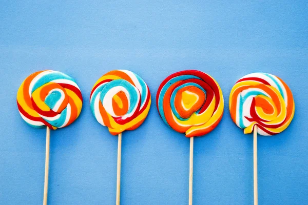 Färgglada lollipop på en blå bakgrund. Röda, vita och blå ränder på en godis. Minimal koncept. Candy shop-serien. — Stockfoto