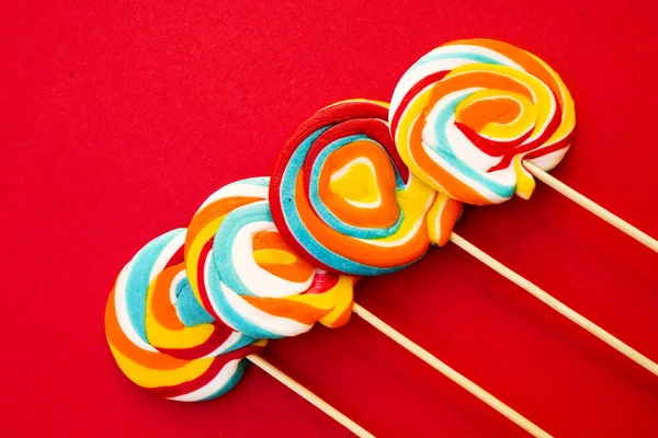 Colorful spiral lollipop on a red background — Stock Photo, Image