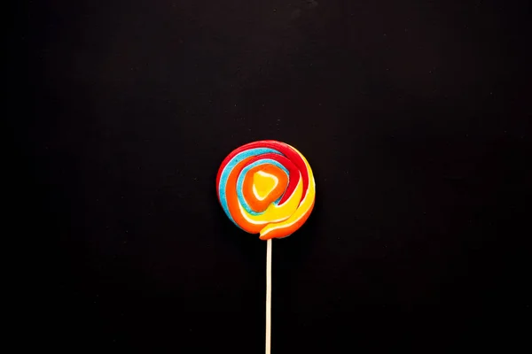 Pirulitos de frutas coloridas em um fundo preto, lanche insalubre, mas delicioso para crianças , — Fotografia de Stock