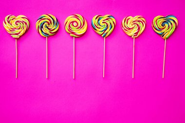 Çok renkli, farklı tatlılar, pembe arka planda lolipoplar. Uzayı kopyala Üst görünüm, tatlı konsepti
