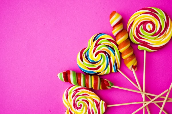 五颜六色不同的糖果粉色背景上的棒棒糖复制空间 甜蜜的概念 — 图库照片