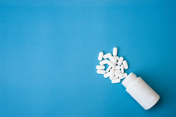 Ліки таблетки і пляшка ліків ізольовані на синьому фоні. Вид зверху — стокове фото