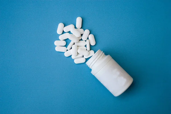 Comprimidos de medicamento e frasco de medicamento isolado sobre fundo azul. Vista superior — Fotografia de Stock