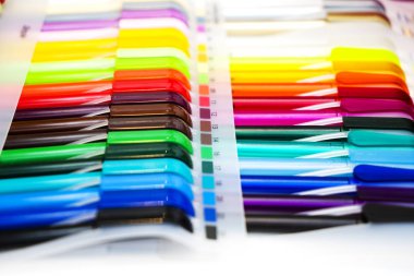 Beyaz masadaki çok renkli plastik tükenmez kalemler.