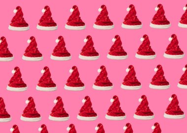 Pattern made of red Santa Claus hat on pink background. Christmas concept. Flat lay. Holiday, New year background concepts