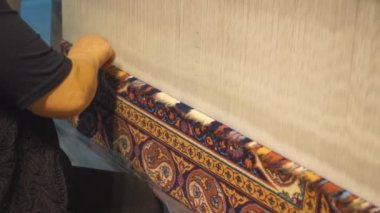 Makinede örgü ören halı ustası kadın. El yapımı halılar örüyorlar. Azerbaycan ustaları