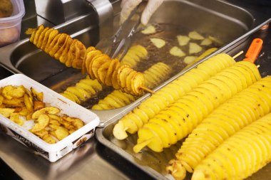 Ahşap çubuk üzerinde sarmal şeklinde patates kızartması. Altın rengi metal tepsi üzerinde piknik sırasında yalan kadar patates kızarmış. Patates chipsy kaşifi