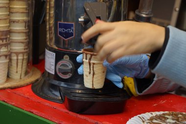 girl bartender pours hot chocolate in a glass an industrial espresso machine.