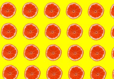 set of red grapefruit slices on yellow background, healthy food.