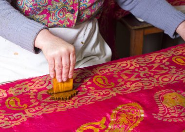 Kadın usta, çizimleri kalagay, oryantal, Türk ipek eşarplarına koyuyor..