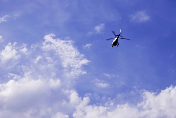 Helicopter flying in the blue cloudy sky. — Stock Photo, Image