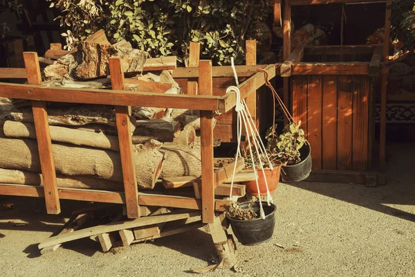 Un vieux chariot en bois avec une cruche en argile et des stands de bois de chauffage dans la cour . — Photo