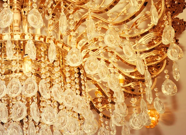 Beau lustre en cristal avec des ampoules lumineuses suspendues au plafond . — Photo