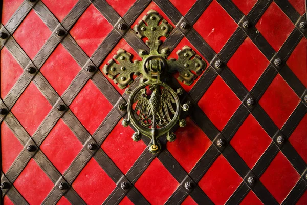 Una manija forjada negra en la puerta de hierro roja. Puerta antigua vintage con asa de hierro . — Foto de Stock