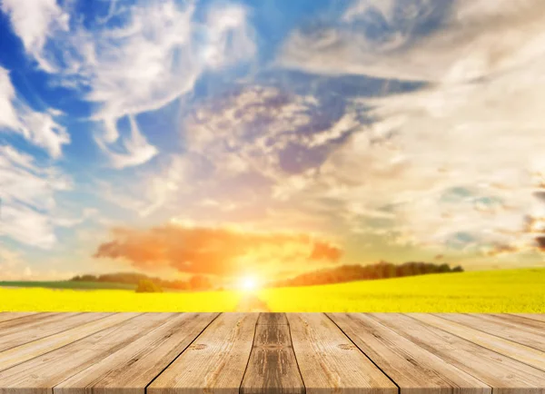 Mavi gökyüzü ile ayçiçeği alanındaki boş ahşap masa. ürün görüntüleme şablonu için arka plan