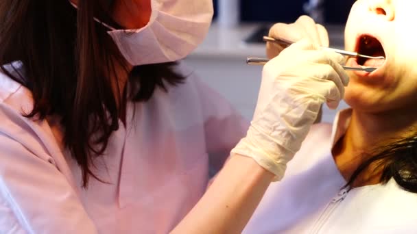 Une femme dentiste travaille avec une patiente. Les médias. Femme dentiste examine et traite les dents des patients avec un équipement dentaire professionnel . — Video