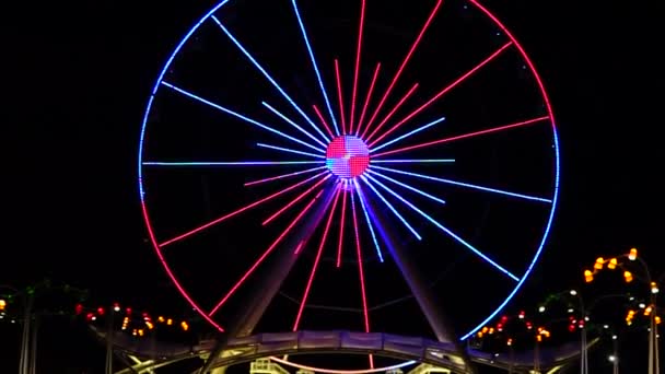 Reuzenrad loopt in de nacht, verlicht door de lichten, kleurrijke looplichten op de grote carrousel. — Stockvideo