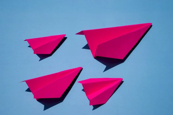 Aerei di carta rosa o aereo di carta Origami su sfondo blu Vista dall'alto con posto per testo, concetto di concorrenza commerciale — Foto Stock