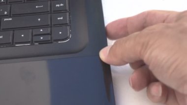 Bir adamın eli bilgisayarın sürücüsünü açar ve diski yerleştirir.