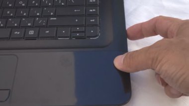 Bir adamın eli bilgisayarın sürücüsünü açar ve diski yerleştirir.