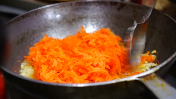 Женщина готовит тушеную капусту и морковь на сковороде. — стоковое видео