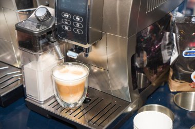 Kahve makinesi, cam bardağa sütlü espresso döker. Cappuccino yapma işlemi.